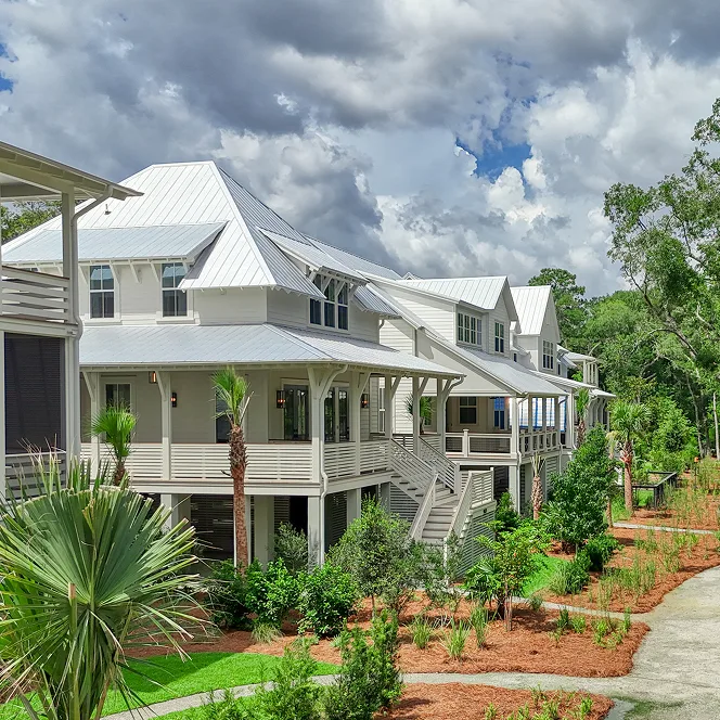 Exterior of a row of large white coastal homes on a sunny day